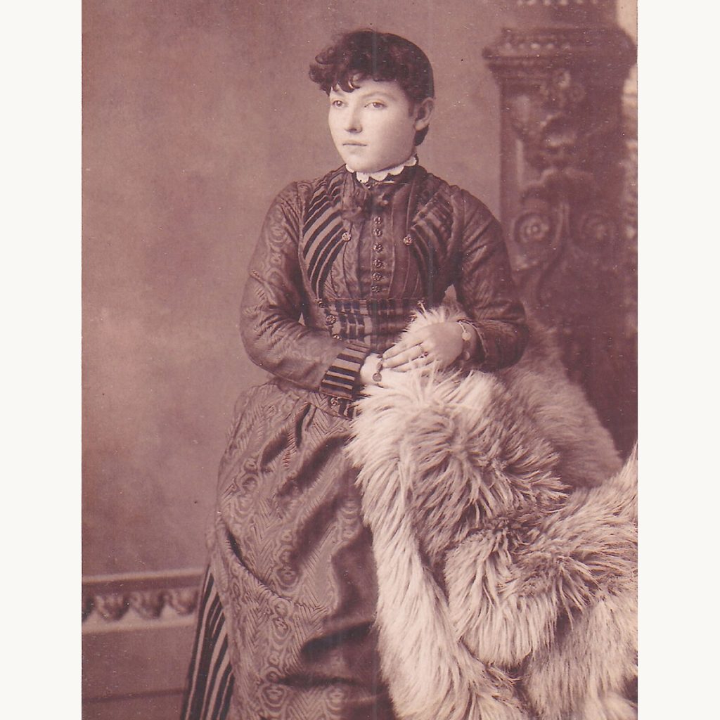 Victorian-era portrait of a woman wearing a patterned dress and fur throw.