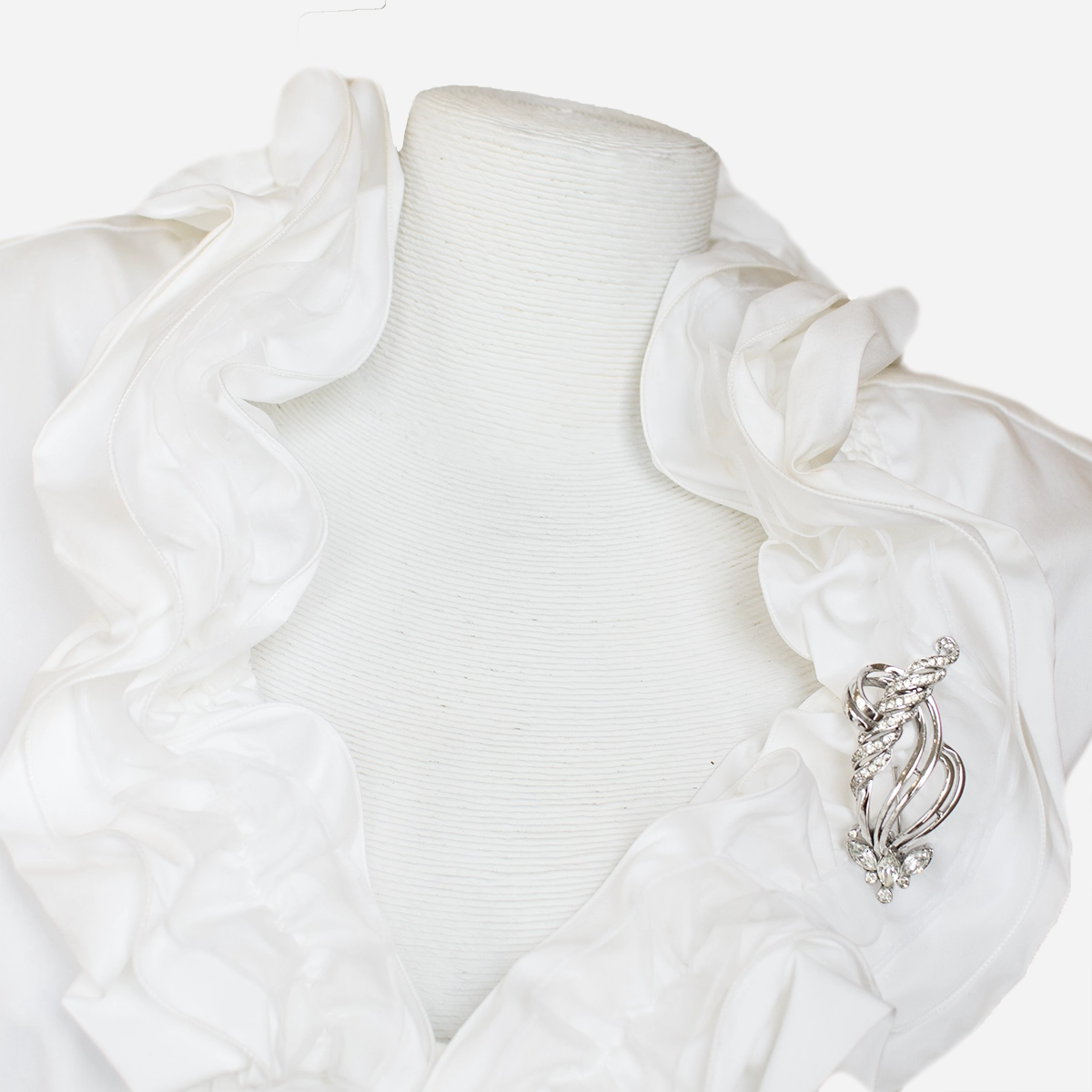 Vintage Mazer Bros rhinestone brooch pinned to a white ruffled blouse, showing its sparkling silver and crystal design.