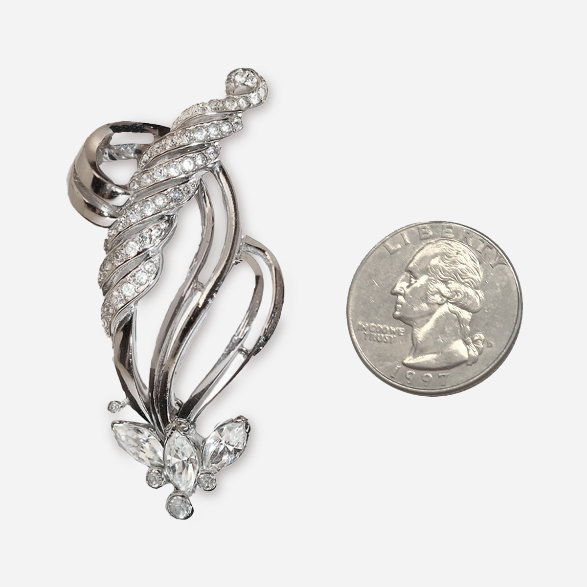 Vintage Mazer Bros rhinestone brooch pinned to a white ruffled blouse, showing its sparkling silver and crystal design.