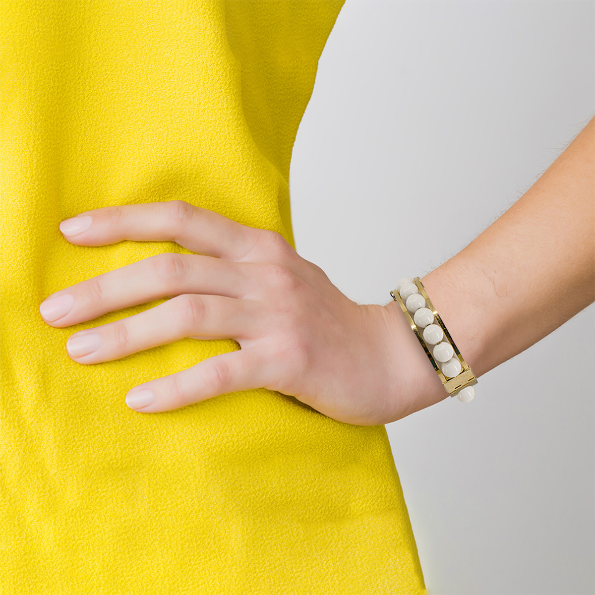 modernist open work gold metal bracelet, model wearing yellow dress