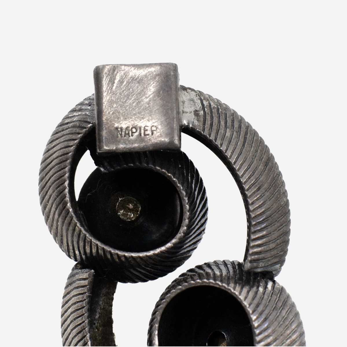 Close-up of Napier hallmark on vintage silver-tone bracelet clasp, showing textured swirl link detail
