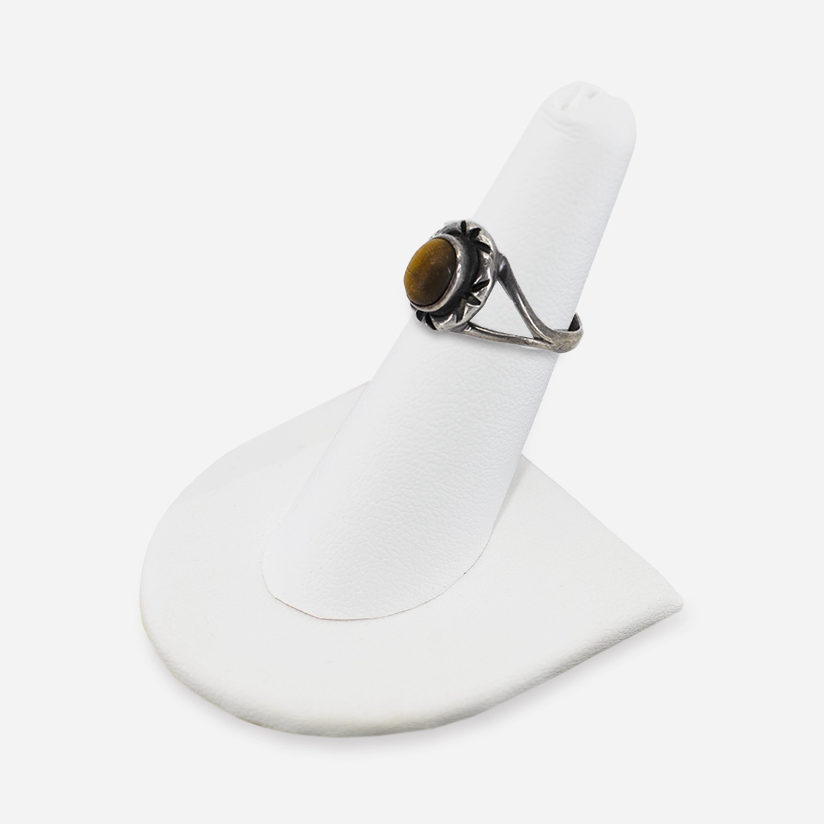 Three-quarter angle of sterling silver tiger’s eye ring on white background, highlighting starburst setting.