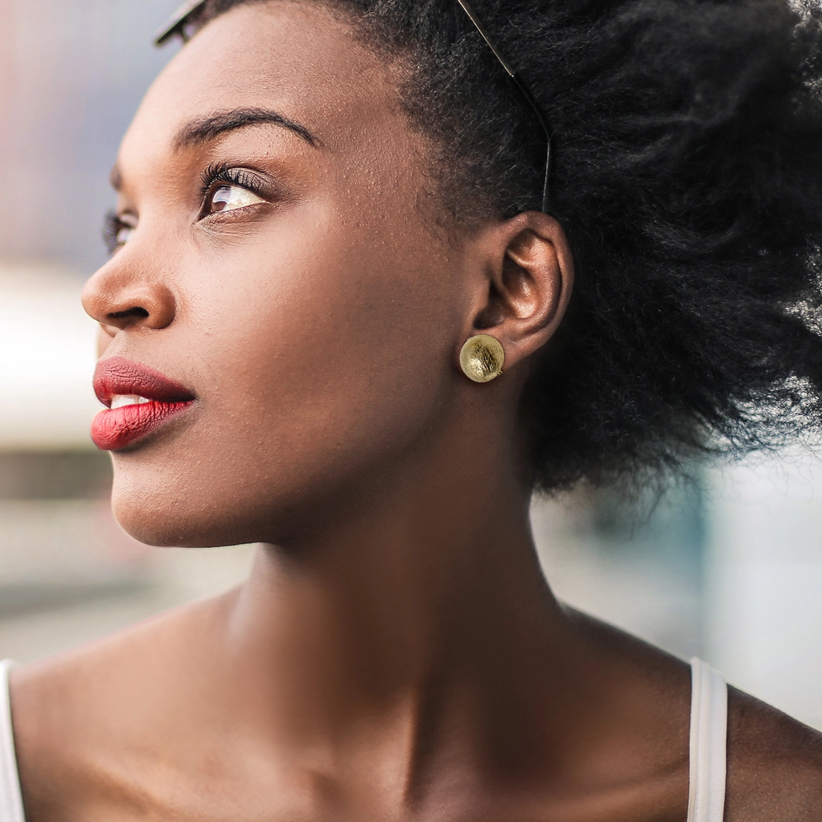 Woman wearing 1950s brushed gold button earrings with wingback clips.