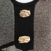 Detail shot: Close-up of faux-stone buttons with gold wrap detail on black trim.
