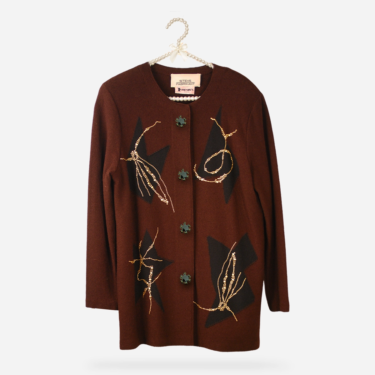 Vintage 1980s Steve Fabrikant brown knit jacket with black abstract insets and gold stud decoration hanging on a pearl hanger.