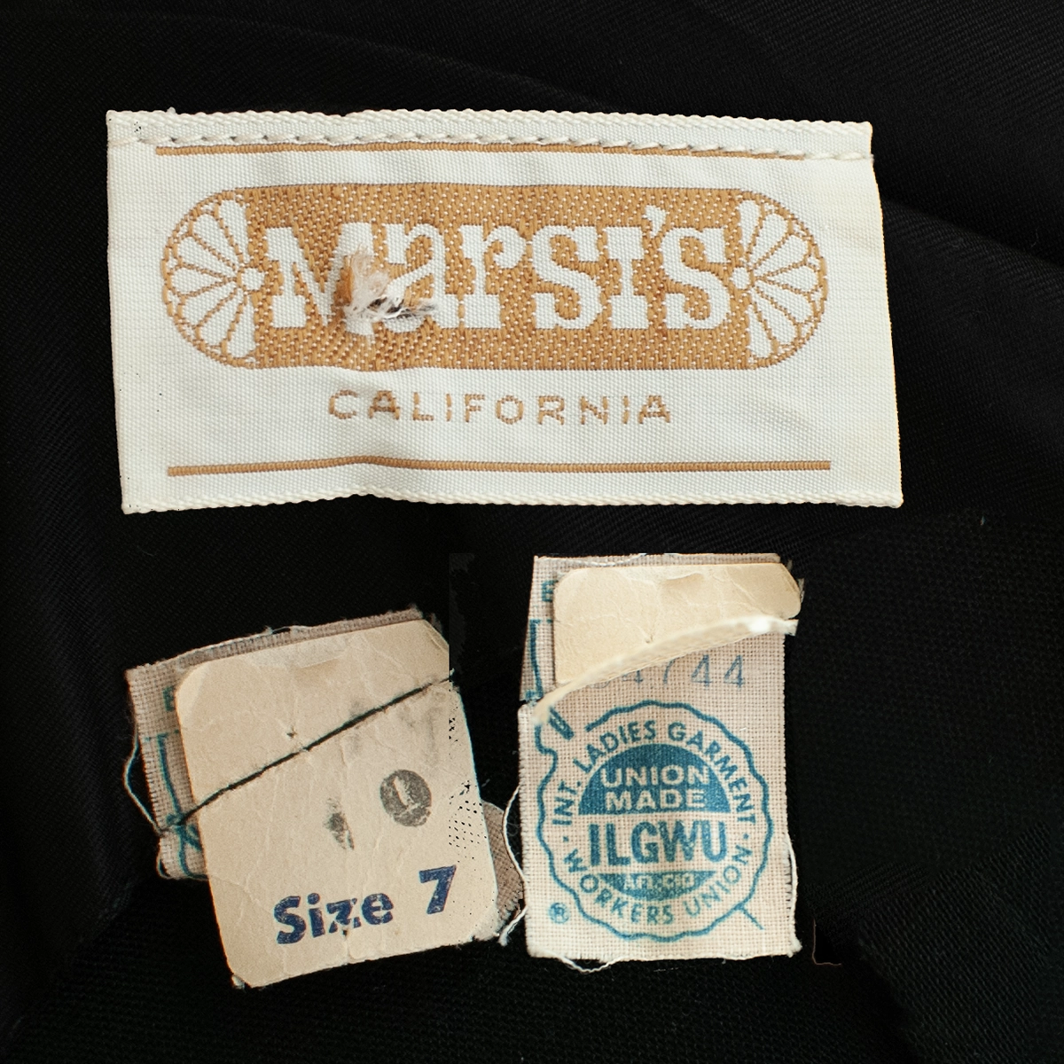 Label close-up: Marsi’s California label and ILGWU union tag on vintage 1960s black cocktail dress.