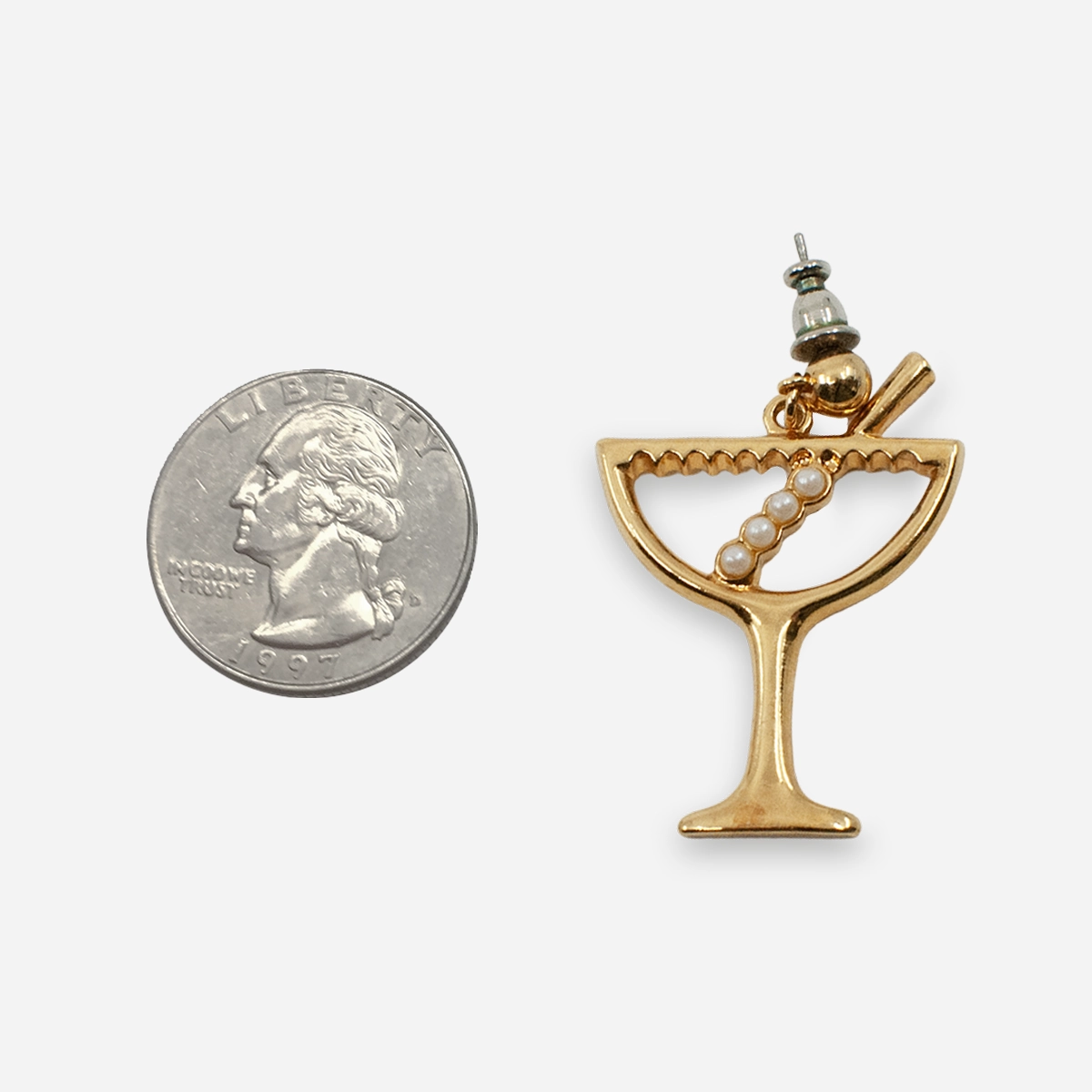 Single martini-glass earring beside a quarter for scale