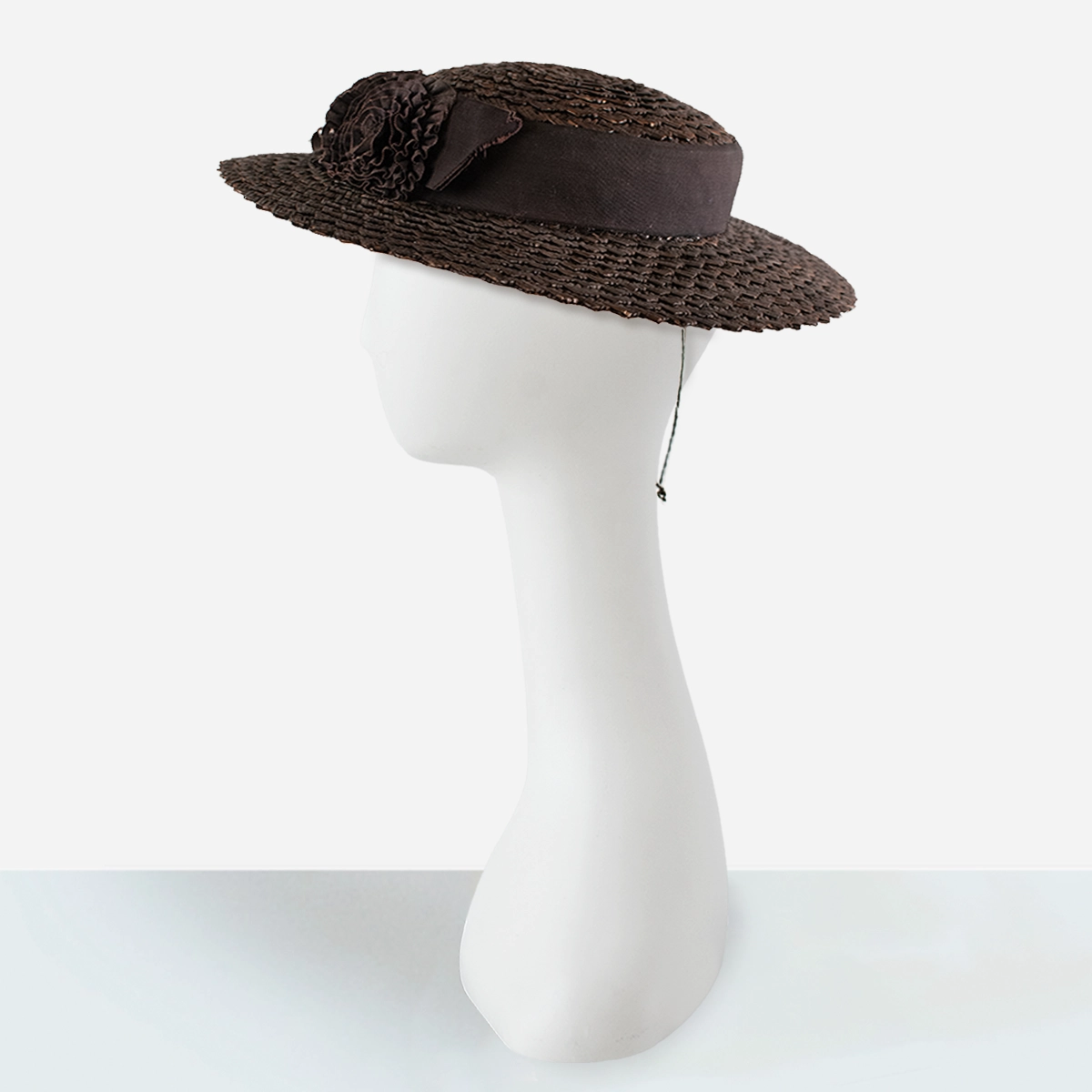 Side view of vintage 1930s brown straw hat with ruffled ribbon flowers.