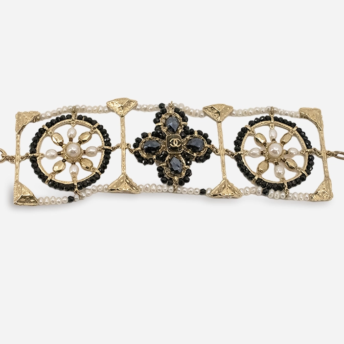 Close view of Chanel bracelet showing pearl edging and crystal quatrefoil.