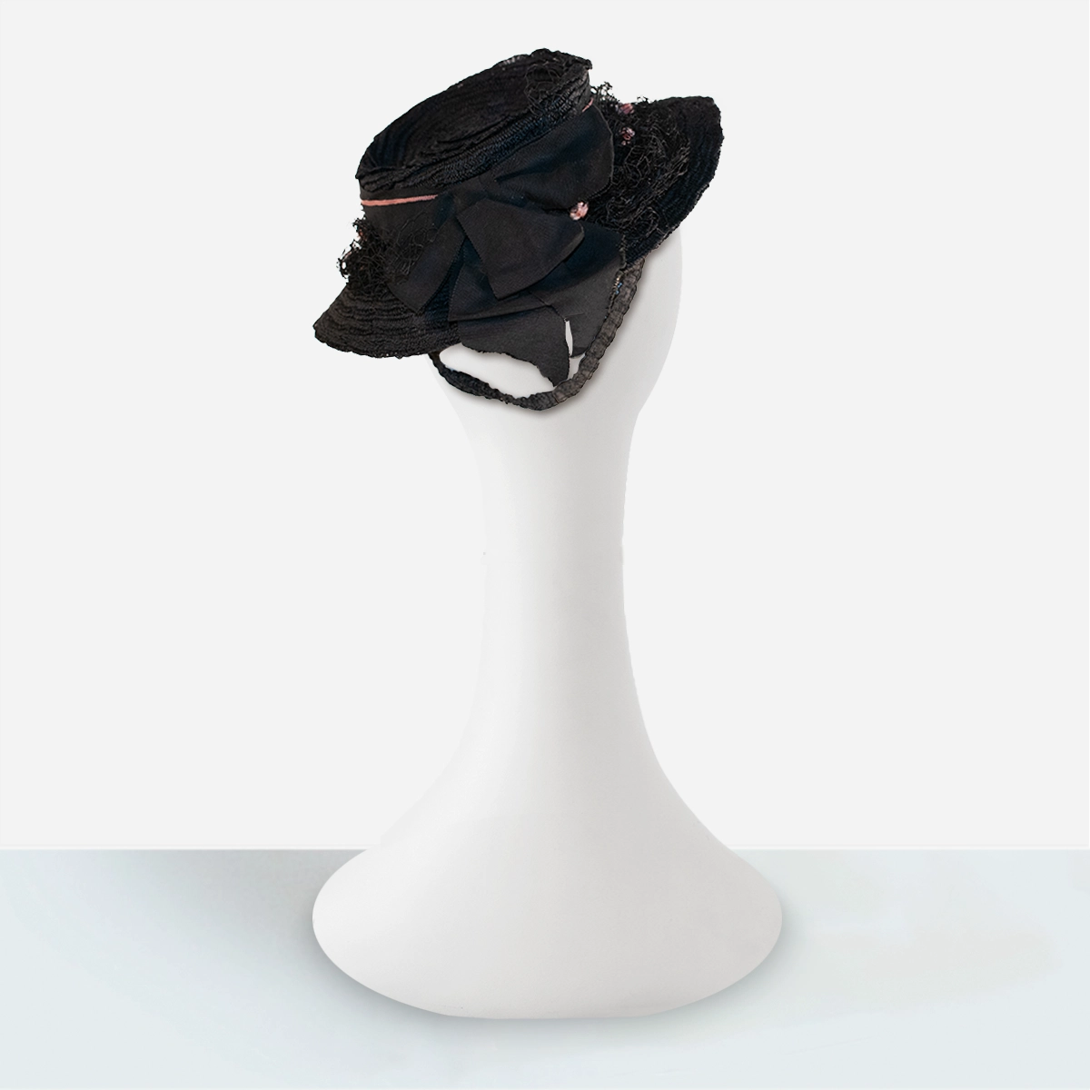 Rear angle of 1930s black straw tilt hat with bow placement.