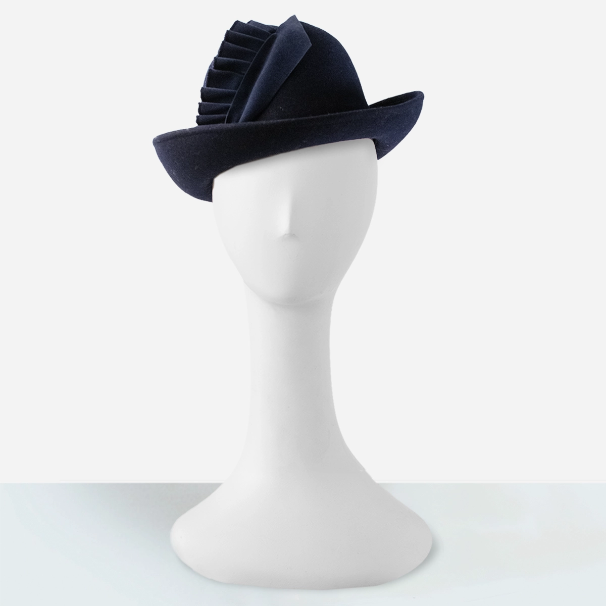 Early 1960s navy blue felt hat on mannequin, showing directional velvet trim.
