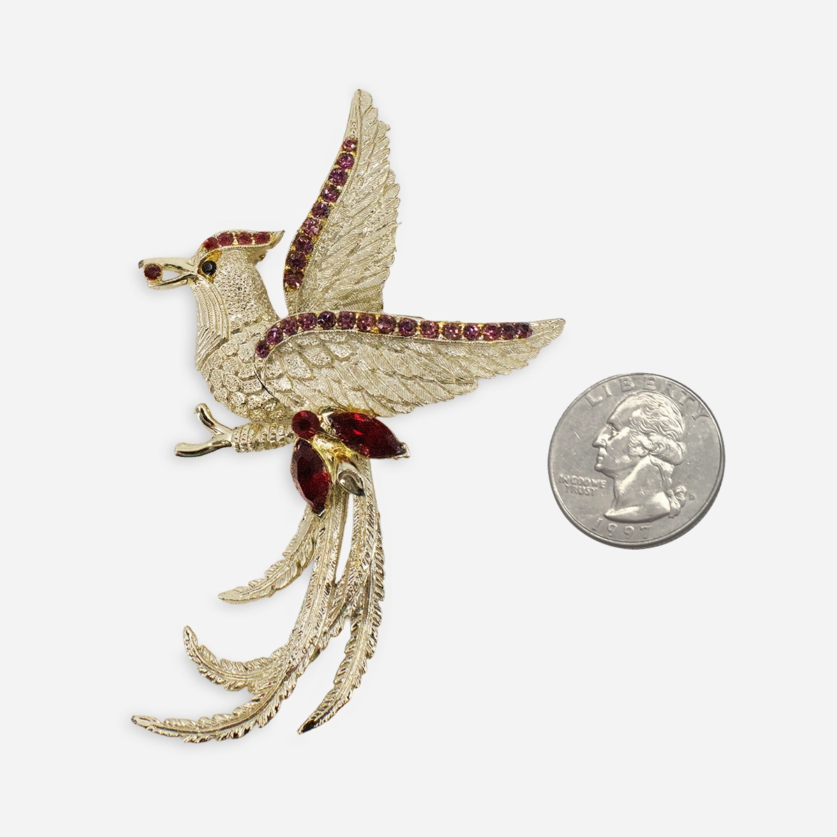 Gold tone bird brooch with long feather tail red stones with quarter for size
