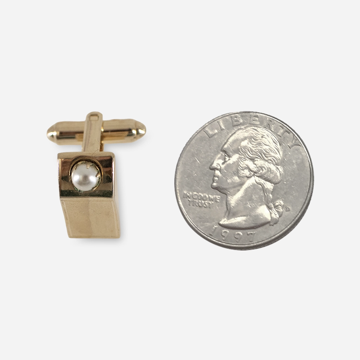 Vintage goldtone pearl cufflink shown beside a quarter for size comparison.