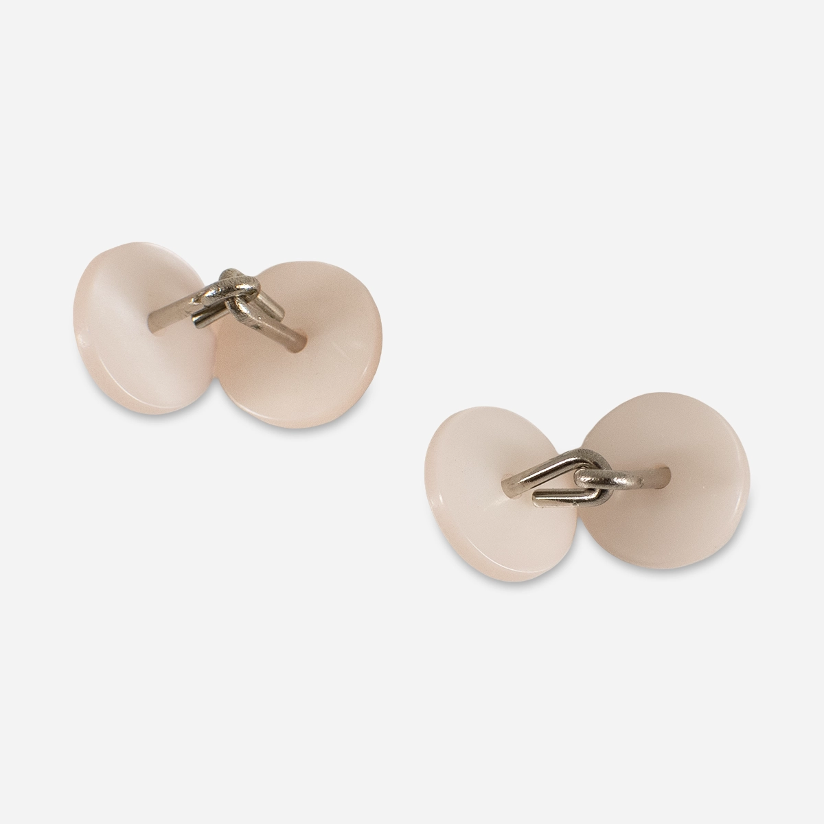 Pair of pearlized pink button cufflinks with fixed bridge construction on light background.