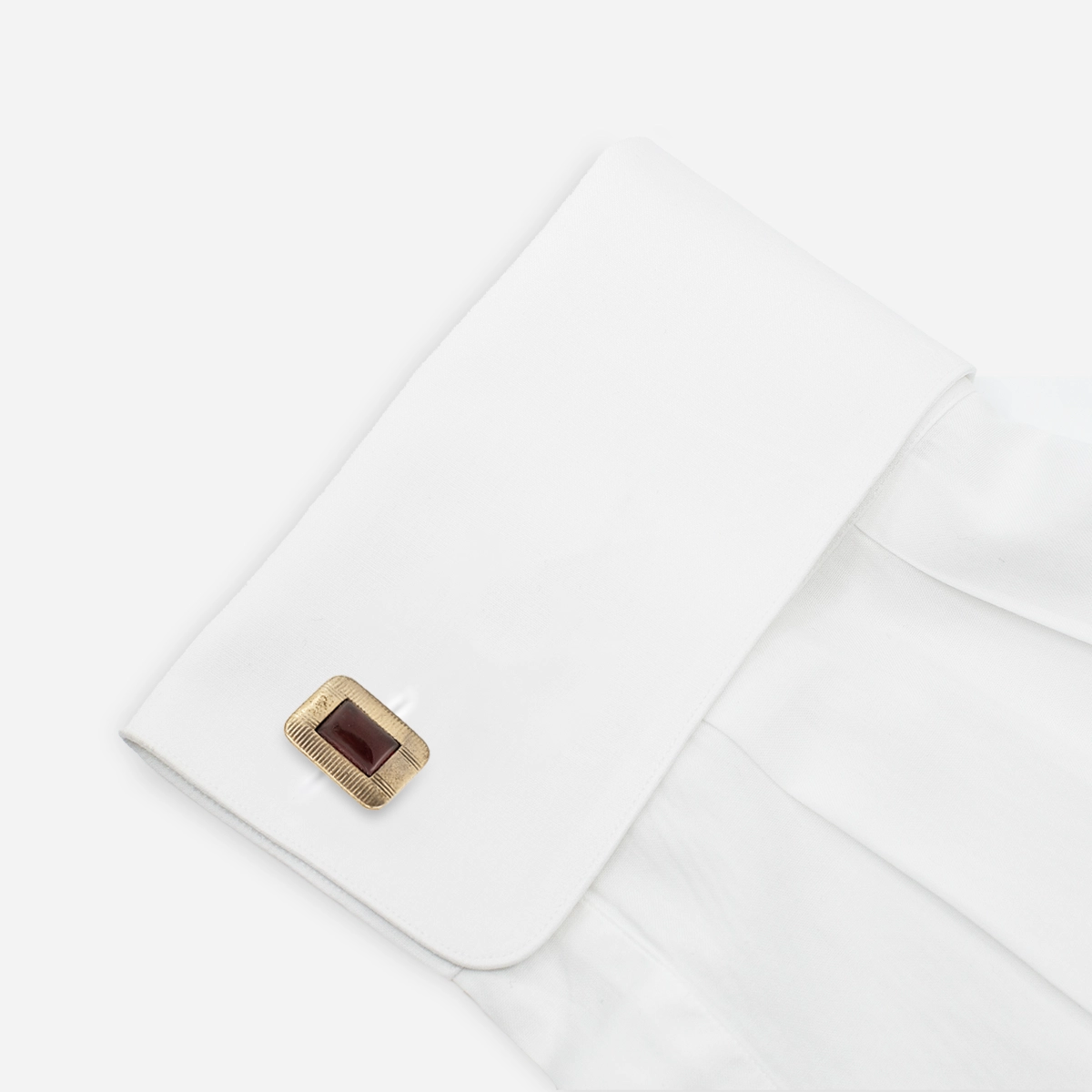 Vintage red and gold-tone cufflink shown on white French cuff shirt.