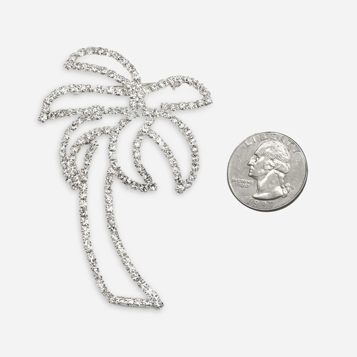 Vintage rhinestone palm tree brooch shown with quarter for scale, measuring approximately 3 inches by 2 inches.