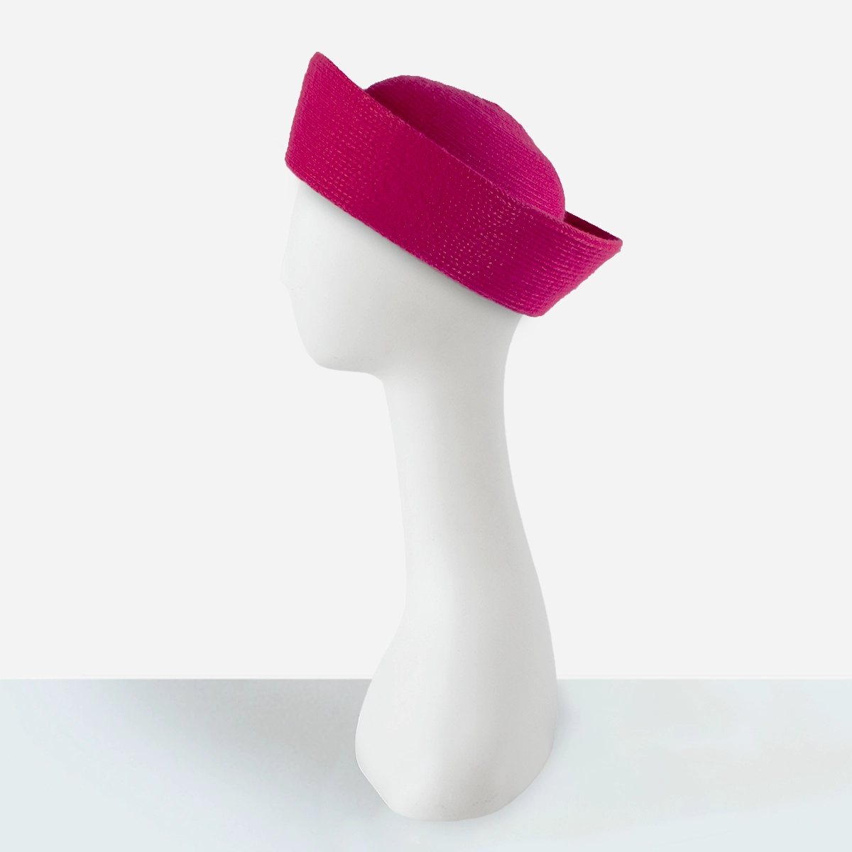 Side view showing the rounded crown and sculptural upturned brim of the pink Breton hat.