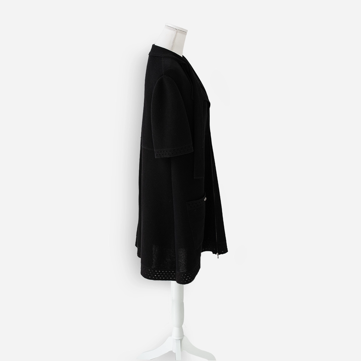 Chanel Black Perforated Side view of Chanel black short sleeve knit jacket showing textured cotton fabric, wide collar, and patch pocket.
