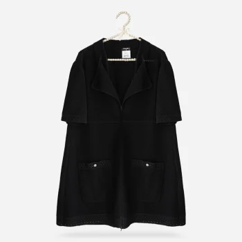 Chanel black cotton knit jacket shown flat on pearl hanger with short sleeves, zip front, wide collar, self neck tie, and patch pockets.