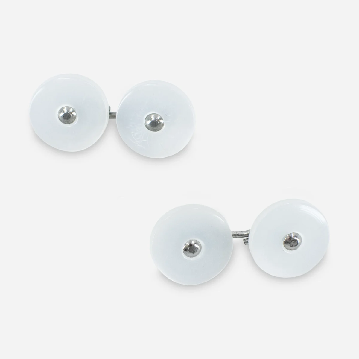 White lucite disk cufflinks copy Close view of pearlized white Lucite cufflinks with round button fronts and silver tone metal centers.