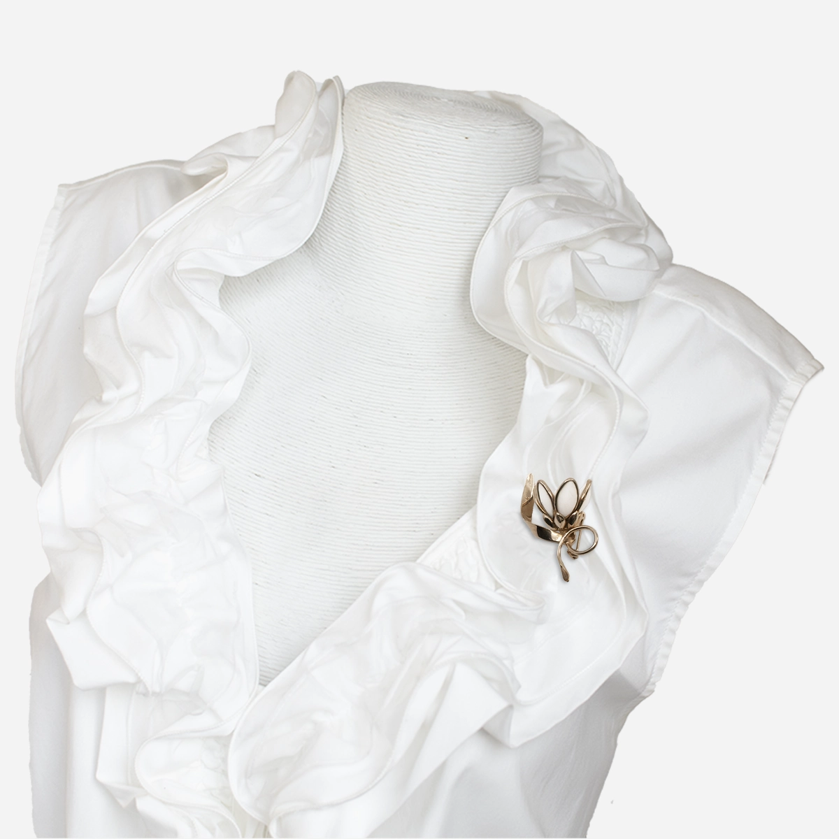 Vintage white milk glass flower brooch worn on a ruffled white blouse.