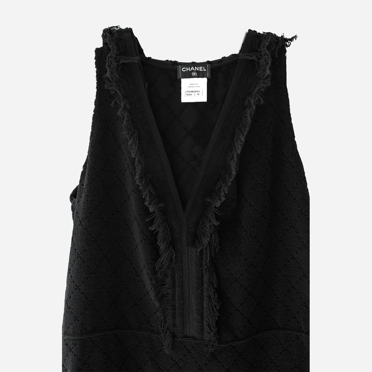 vintage chanel black minidress Matelassé Fringe Close-up of Chanel black sleeveless mini dress showing V neckline, fringe trim, and designer label.