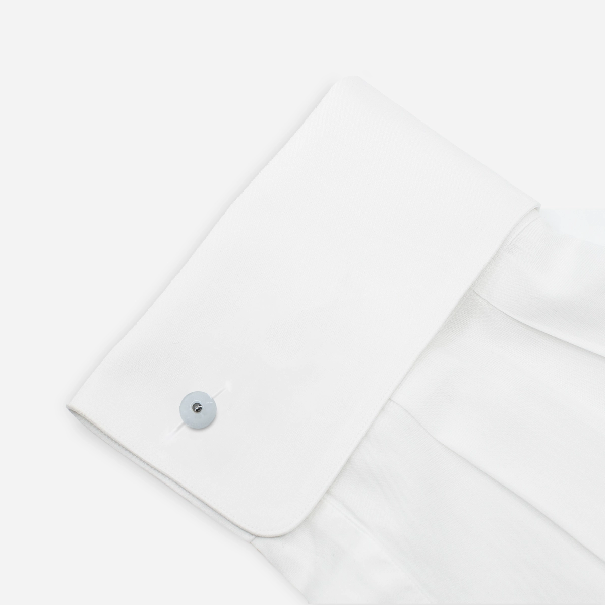 1950s white Lucite cufflink with pearlized button design fastened on a white French cuff shirt.