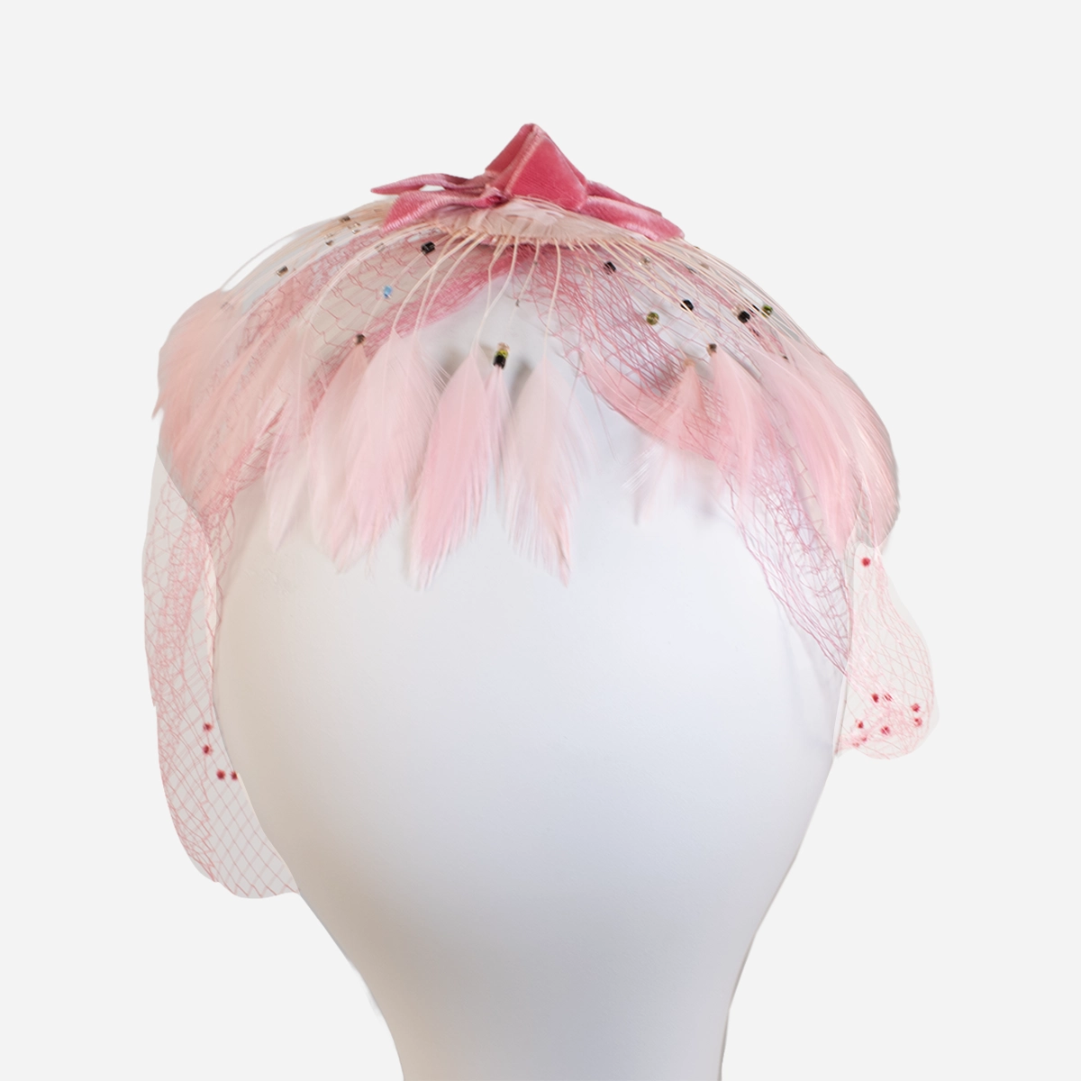 1950s pink veil netting hat Close overhead view of pink netting, feather trim, bead accents and velvet bow